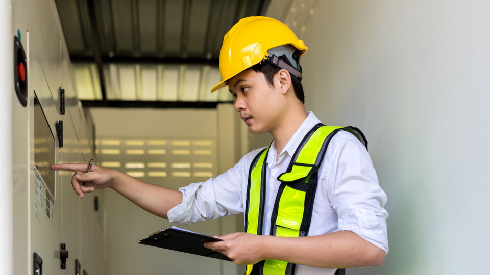 A factory worker following a checklist on a clipboard during a quality control inspection